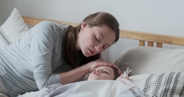 Yakın plan, şefkatli bir anne sıcak alnına dokunup vücut ısısını ölçüyor. — Stok video