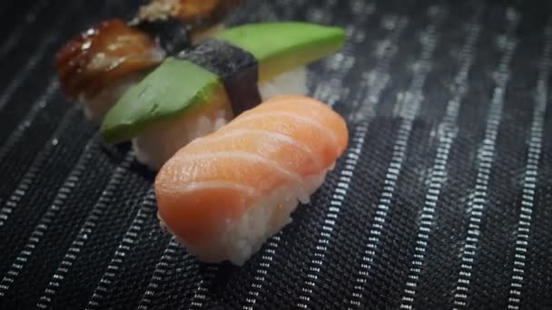 Privire de sus imagine de closeup de rulouri gustoase de sushi umplute cu somon crud de avocado, anghilă. Varietate de tipuri de sushi cu pește, legume și orez. Restaurantul Sushi, livrarea de alimente. Focalizare selectivă — Videoclip de stoc