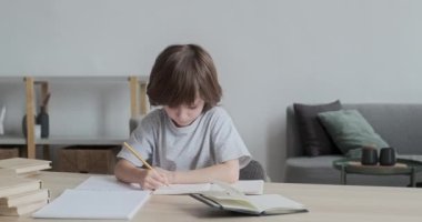 Düşünceli, düşünceli, özenli ve çalışkan 6 yaşındaki bir çocuk evde yazmayı ve çizmeyi öğreniyor..