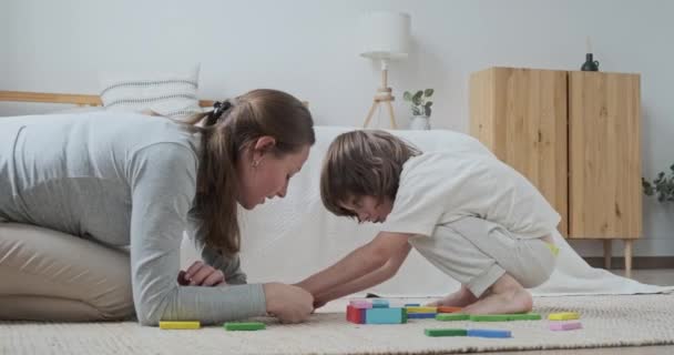 遊び心のある女性乳母と男性の子供構築とともに木製多色ブロック — ストック動画