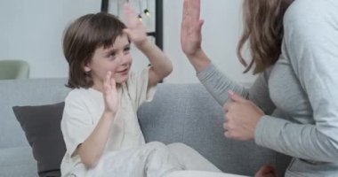 Neşeli Avrupalı çocuk annesine el çırpıyor ortaklık jesti yapıyor ve eğleniyor.
