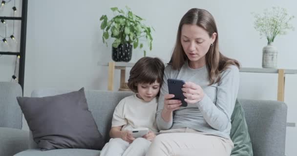 Γέλια γυναίκα γραπτών μηνυμάτων στο τηλέφωνο αρσενικό παιδί παίζει online παιχνίδι smartphone — Αρχείο Βίντεο