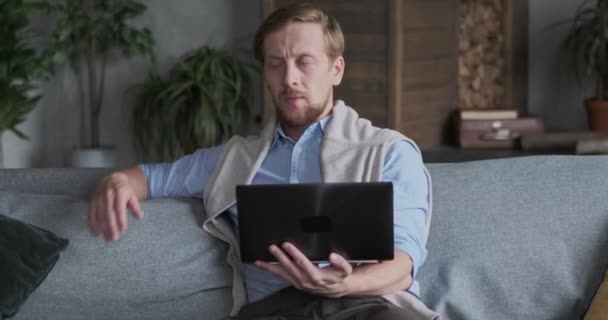 Businessman sitting on coach and texting on laptop, communicating with clients — Stock Video