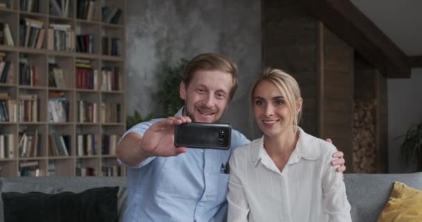 Adorable pareja hablando videollamada en línea juntos abrazando el uso sonriente smartphone en el apartamento — Vídeos de Stock