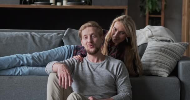 Sonriente pareja de matrimonio disfrutando de la actividad de ocio de fin de semana tumbados en el sofá juntos en casa — Vídeos de Stock