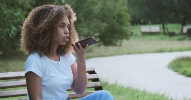 Yakın plan Afrikalı Amerikalı kadın ses tanıma mesajı kaydediyor. Sohbet için akıllı telefon kullanıyor.