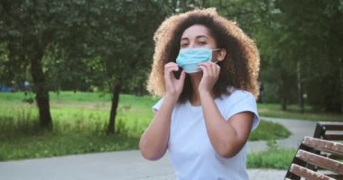 Genç Afrikalı kadın maskesini takıp çıkarıyor ve neşeyle özgürce nefes alıyor.,