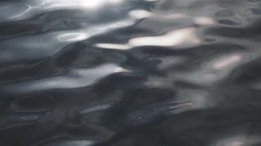 Dramatik koyu mavi su yüzeyi. Güneş ışığı parlıyor. Yakın plan. Fırtınalı su sıvısı pürüzsüz