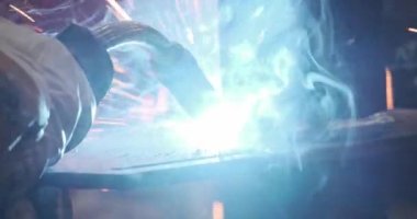 Üniformalı, koruyucu elbiseli, kasklı, eldivenli metal kaynaklı parlayan ışıklar.