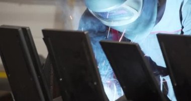 Üniformalı, koruyucu elbiseli, kasklı, eldivenli metal kaynaklı parlayan ışıklar.