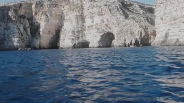 Blaue Meereswellen schlagen braune, hügelige Küste mit felsigen Klippen — Stockvideo