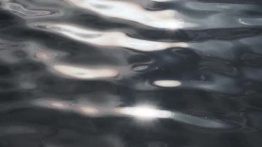 Dramatik koyu mavi su yüzeyi. Güneş ışığı parlıyor. Yakın plan. Fırtınalı su sıvısı pürüzsüz