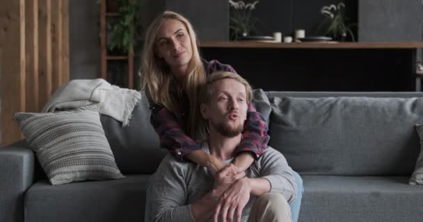 Пара наслаждающихся медовым месяцем вместе отдыхает на удобном диване в роскошной квартире — стоковое видео