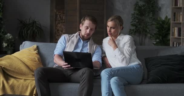 Parceiro de negócios casal na moda trabalhando juntos usar laptop no aconchegante apartamento de navegação na web de pesquisa — Vídeo de Stock