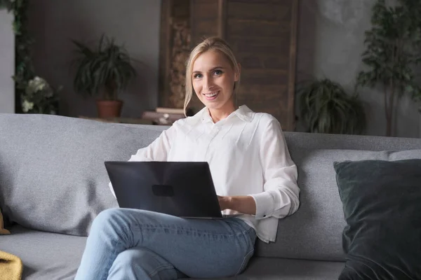 Freelancer mulher jovem pensativo digitando no sofá sentado laptop. Imagens Royalty-Free
