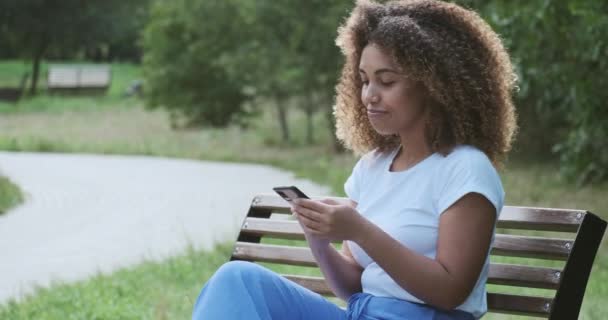Улыбающаяся афроамериканка современная, непринужденная леди жестикулирует эмоционально разговаривая по телефону — стоковое видео