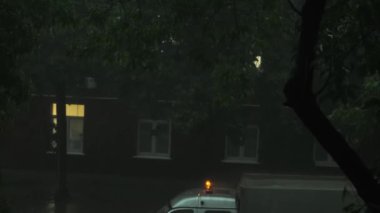 Gece şehir otoyolu, doğal yeşil ağaçlarla çevrili, sağanak suyla kaplı.