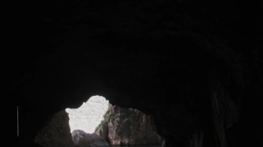 Gri kahverengi kayalık uçurum tüneli güneşli bir günde deniz suyunun üzerinde