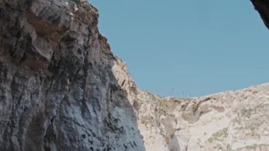 Gri kahverengi kayalık uçurum tüneli güneşli bir günde deniz suyunun üzerinde