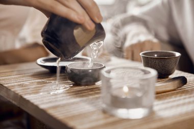 Çin çay seremonisinin yakın çekimi. Masanın üzerinde bir gaiwan, bir kase, bir çaycı ve bir palo santo var.