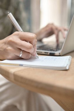 Kafede dizüstü bilgisayarla oturan güzel bir genç kadın portresi. Çevrimiçi öğrenme, yazma, bilgi arama, özet notları. 