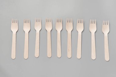 Tahta kaşık, çatal, kağıt bardak gri arka plan. Doğal malzemelerden yapılmış tek kullanımlık sofra takımı. Sıfır israf kavramı, sürdürülebilir yaşam tarzı. Çevre dostu tek kullanımlık sofra takımı