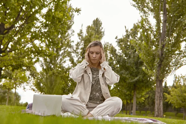 Woman sitting in lotus pose, crossed leg posture (Sukhasana) and meditating in a park. An attractive woman relieves stress by meditating in the park