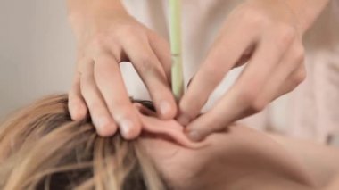 Çıplak kadın masörden kulak mumu alıyor.