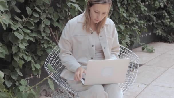 Egy nő ül az asztalnál laptoppal a parkban — Stock videók