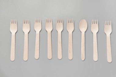 Tahta kaşık, çatal, kağıt bardak gri arka plan. Doğal malzemelerden yapılmış tek kullanımlık sofra takımı. Sıfır israf kavramı, sürdürülebilir yaşam tarzı. Çevre dostu tek kullanımlık sofra takımı