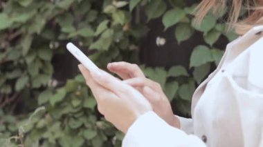 Bir kadın akıllı telefonu elinde tutuyor ve ekrana bakıyor.