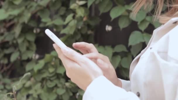 Une femme tient un smartphone dans ses mains et regarde l'écran — Video