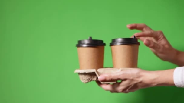 Manos sosteniendo dos tazas de papel marrón con tapa negra — Vídeo de stock