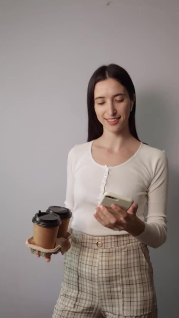 Женщина держит две чашки коричневой бумаги с черной крышкой — стоковое видео