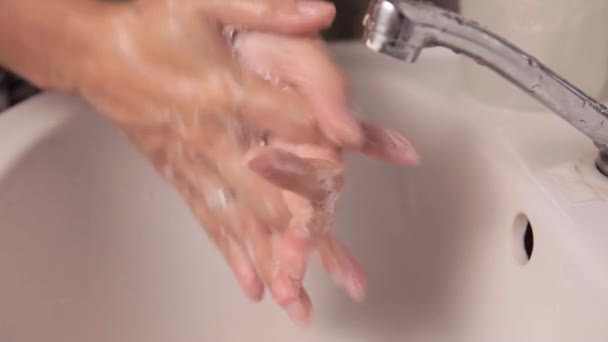 A nő kezet mos a fürdőszobában egy fehér kerámia mosdóban a csap alatt. — Stock videók