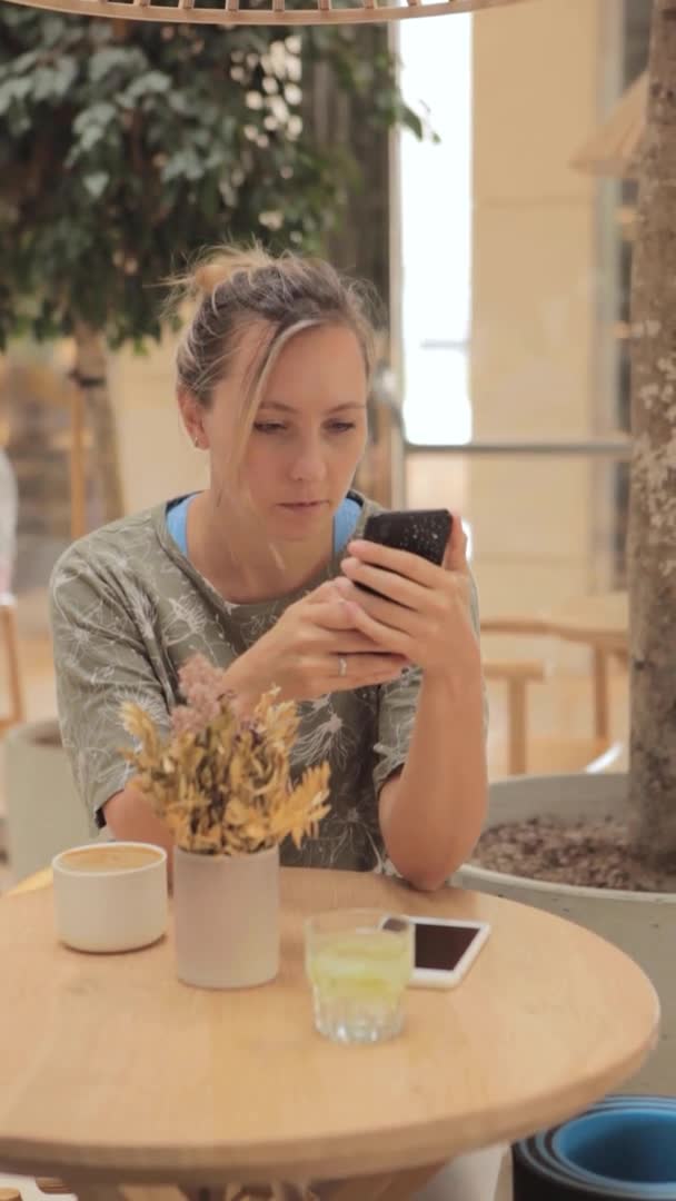 Uma mulher segura um smartphone em suas mãos e olha para a tela — Vídeo de Stock