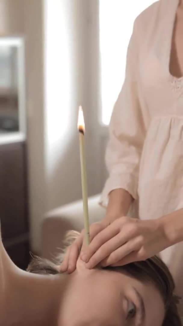 Обнажённая женщина получает ушную свечу от массажиста — стоковое видео