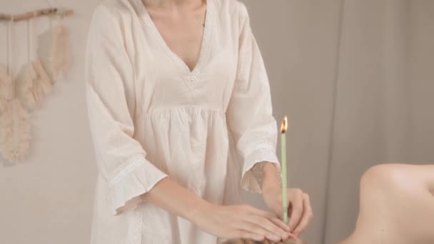 Обнажённая женщина получает ушную свечу от массажиста — стоковое видео