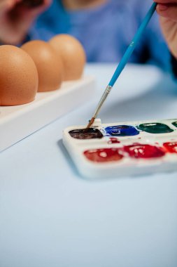Küçük bir çocuk paskalya yumurtası boyuyor..