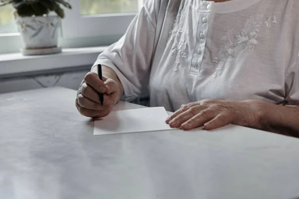 Seniorin schreibt am Küchentisch — Stockfoto