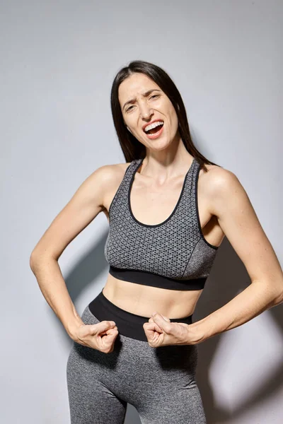 Kobieta w odzieży sportowej pokazuje swoje mięśnie i śmieje się — Zdjęcie stockowe