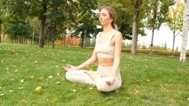 Bir kadın parkta yoga yapıyor.