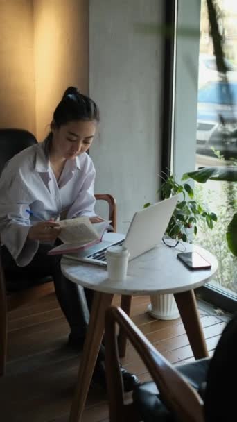 Ázsiai női szabadúszó dolgozik egy kávézóban — Stock videók