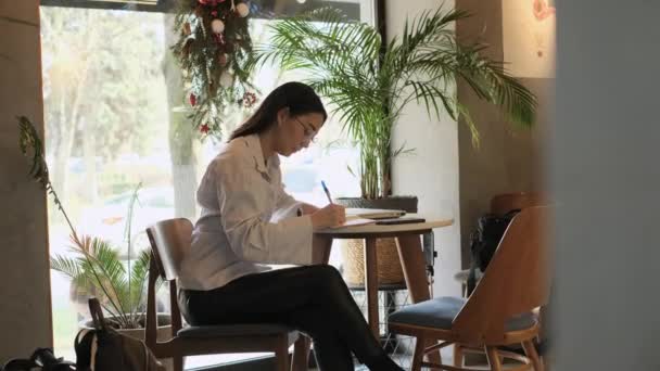 Ασιάτισσα ελεύθερη επαγγελματίας που εργάζεται σε καφετέρια — Αρχείο Βίντεο