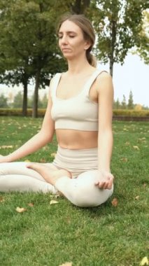Bir kadın parkta yoga yapıyor.