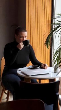 Bir kadın kafede oturur ve dizüstü bilgisayarda çalışır..