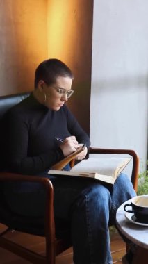 Bir kadın kafede oturuyor ve tablette çalışıyor..