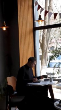 Bir kadın kafede oturur ve dizüstü bilgisayarda çalışır..