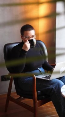 Bir kadın kafede oturuyor ve tablette çalışıyor..