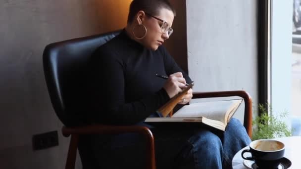Eine Frau sitzt in einem Café und arbeitet an einem Tablet. — Stockvideo